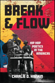 Three hip hop artists at a turn table in front of a colorful brick wall.