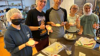 Five people smiling, holding shaped dough
