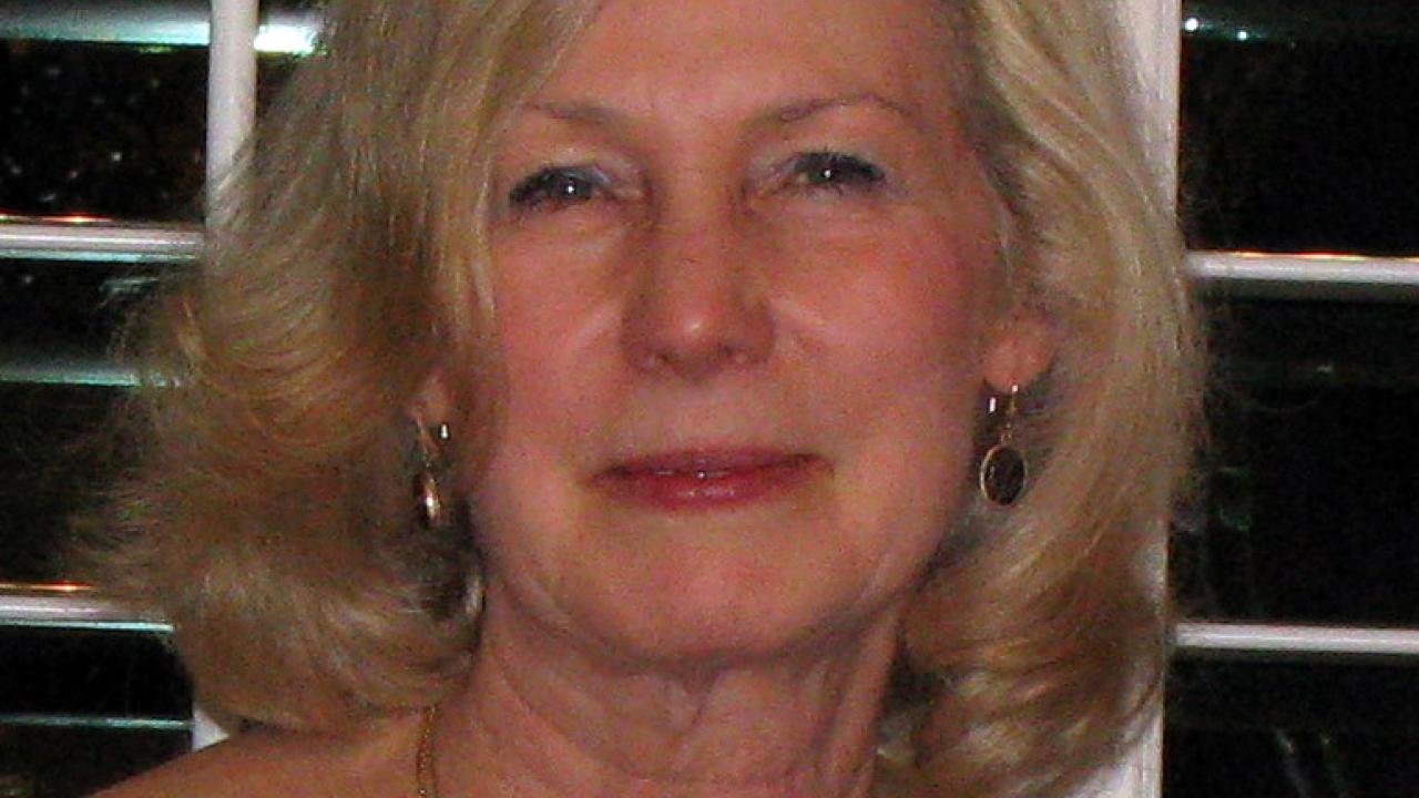 A woman smiling at the camera with shoulder length grey hair