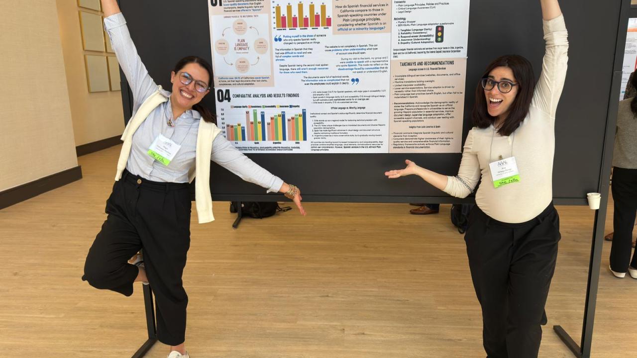 2 graduate students stand near their poster