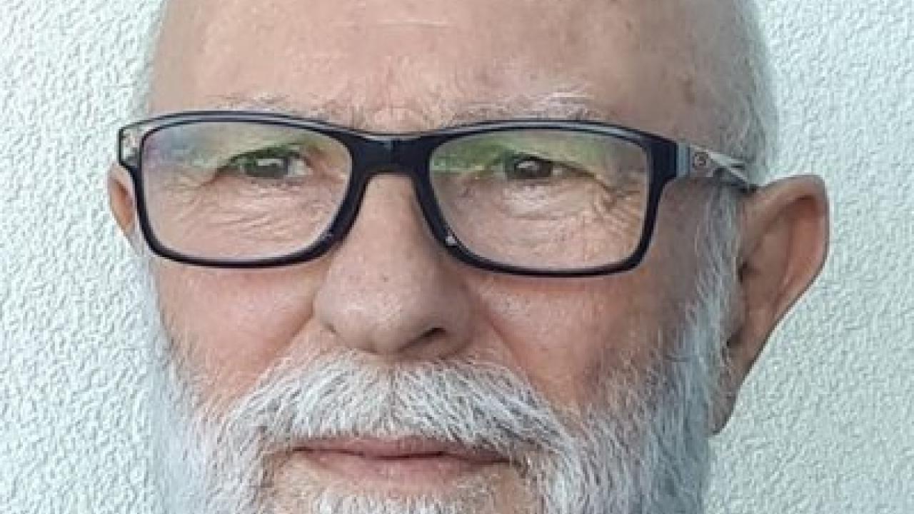 Portrait of a man with a grey beard wearing glasses