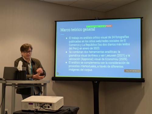 man in front of screen presenting.