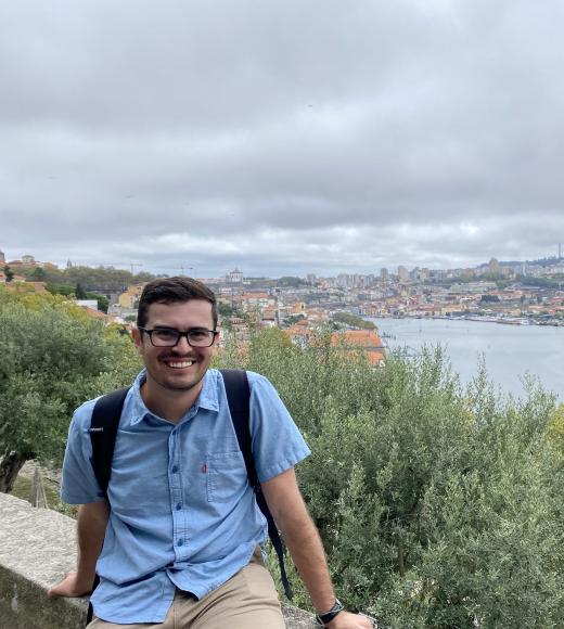 A photo of a man with an old city in the background, and a river