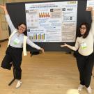 2 graduate students stand near their poster