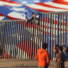 People pose for photos at the Mexico/U.S. border wall.