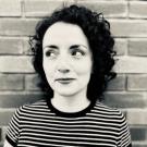 A black and white photo of Daniela in front of a brick wall in a striped shirt