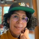 A picture of an artist wearing a baseball cap and glasses.